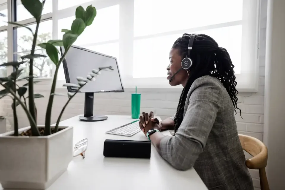 A professional with headphones looking at a computer monitor, possibly engaged in asynchronous communication.